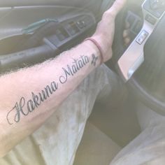 a man with a tattoo on his arm driving a car