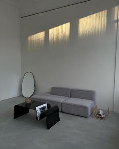 a living room with a couch, mirror and other items on the floor in front of a white wall