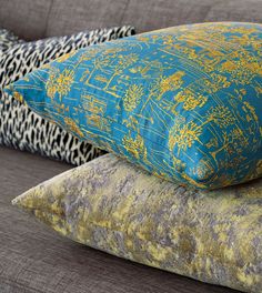 three pillows are stacked on top of each other in different colors and patterns, along with one another