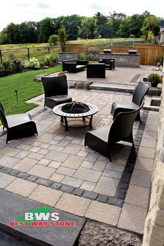 an outdoor seating area with black chairs and a fire pit in the middle of it