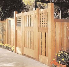 a wooden fence is shown with flowers in the foreground and trees in the background