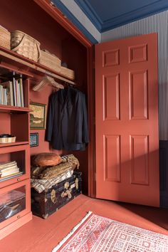 an open red closet with a suit case and suitcase