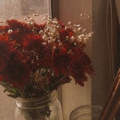 a vase filled with red and white flowers next to a window sill on a windowsill