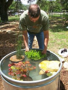 a man standing in front of a barrel filled with water and plants on top of it