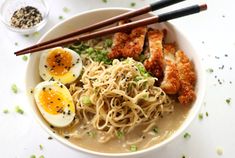 a bowl filled with noodles and meat next to chopsticks on top of a table