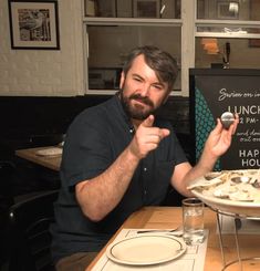 a man sitting at a table with a plate of food in front of him and a sign behind him