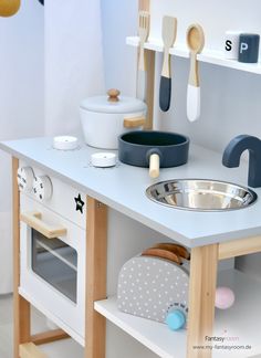 a play kitchen with wooden utensils on the counter