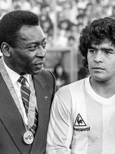 two men standing next to each other in front of a crowd at a soccer game