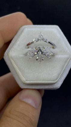 someone is holding an engagement ring with three diamonds on it in a white velvet box