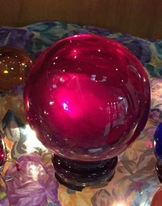 three different colored glass vases sitting on top of a quilted tablecloth with lights in the background