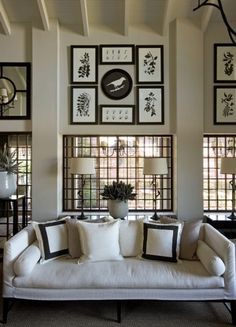 a living room filled with lots of furniture and pictures on the wall above it's windows