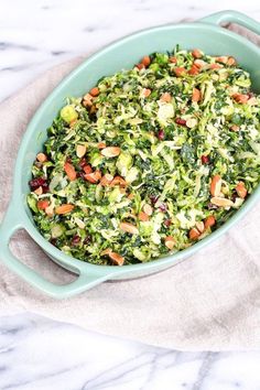 a green casserole dish filled with broccoli, carrots and nuts