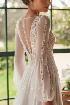 the back of a woman's wedding dress, with sheer sleeves and lace detailing