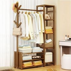 an organized closet with clothes and handbags hanging on the rack in front of a window