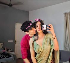 a man taking a picture of a woman in her bedroom while she takes a selfie