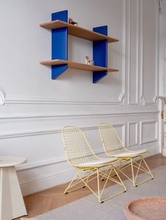 a white chair sitting in front of a blue shelf next to a wall with shelves on it