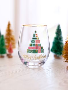 a wine glass sitting on top of a table next to small christmas trees and ornaments