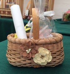 a wicker basket with flowers, candles and other items in it on a table