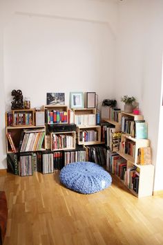 a room filled with lots of books on shelves next to a dog bed in the middle