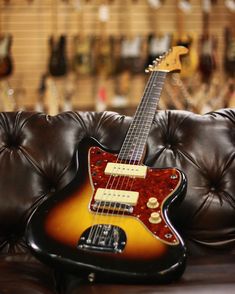 an electric guitar sitting on top of a brown leather couch