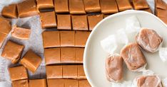 several pieces of peanut butter on a white plate next to some cut up squares and wax paper