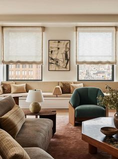 a living room filled with furniture and windows covered in roman blind shades on top of them