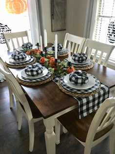 the table is set with black and white plates, plaid napkins and pumpkins