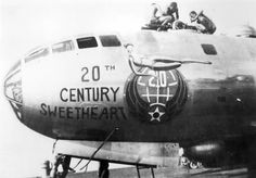 an old black and white photo of people on the nose of a large airplane