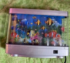 a fish tank with many different types of fish in it on a green cloth covered surface