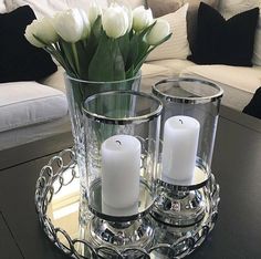 two candles are sitting on a tray with flowers in it