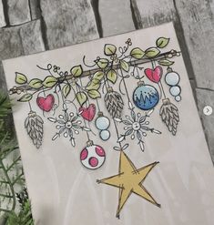 a handmade christmas card with ornaments hanging from a branch and a star on it