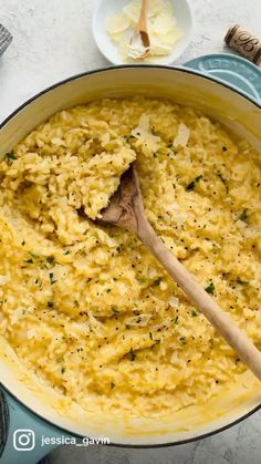 a wooden spoon in a large pot filled with mashed potatoes and parmesan cheese