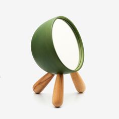 a green magnifying glass sitting on top of a wooden tripod shaped stand