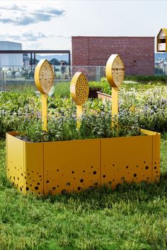 a yellow planter filled with lots of plants on top of a lush green field