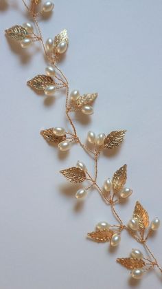 a gold leaf and pearl necklace on a white background