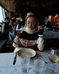 a woman sitting at a table with two glasses of wine