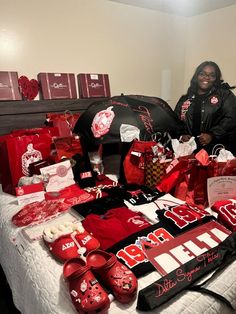 a woman standing next to a bed covered in red items