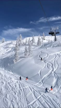 skiers are skiing down a snowy mountain with a ski lift in the back ground