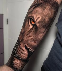 a man's arm with an orange eye and a lion tattoo on the forearm