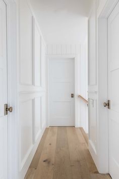 an empty hallway with white walls and wooden floors