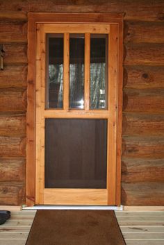 the front door of a log cabin with a brown mat on the floor next to it