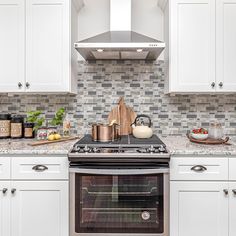 a stove top oven sitting inside of a kitchen next to white cabinets and counter tops