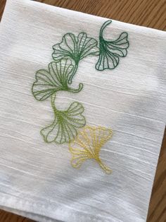 a white napkin with green and yellow designs on it sitting on a wooden table top