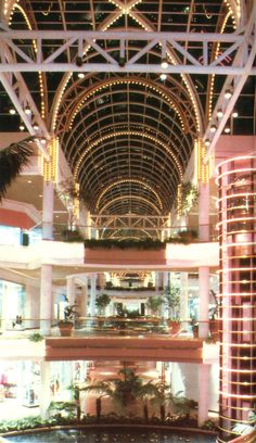 the inside of a shopping mall filled with lots of lights and plants on top of it