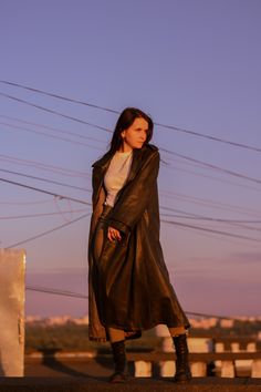 a woman standing on top of a roof next to power lines in the evening time