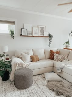 a living room filled with lots of furniture and plants on top of a white rug