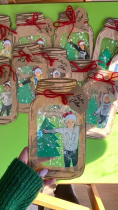 someone is holding up some mason jars with christmas pictures on them and red ribbon around the jar