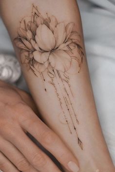 a woman's hand with a flower tattoo on her left arm and the wrist