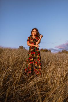 a woman standing in tall grass with her arms crossed