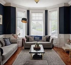 a living room filled with furniture and windows covered in shades of blue, white and brown